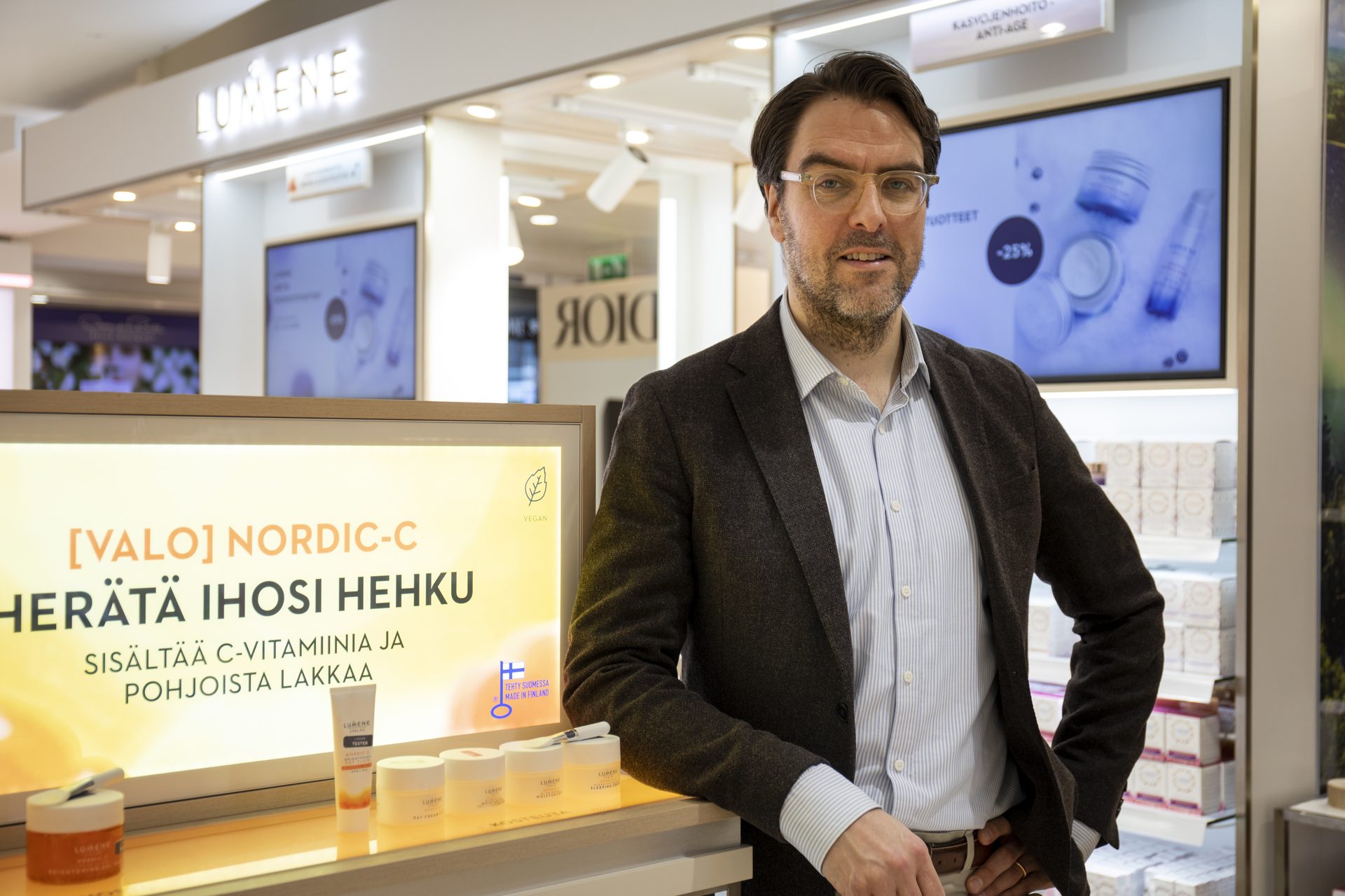 Martti Ala-Jääski at a Lumene counter in front of an orange campaign display