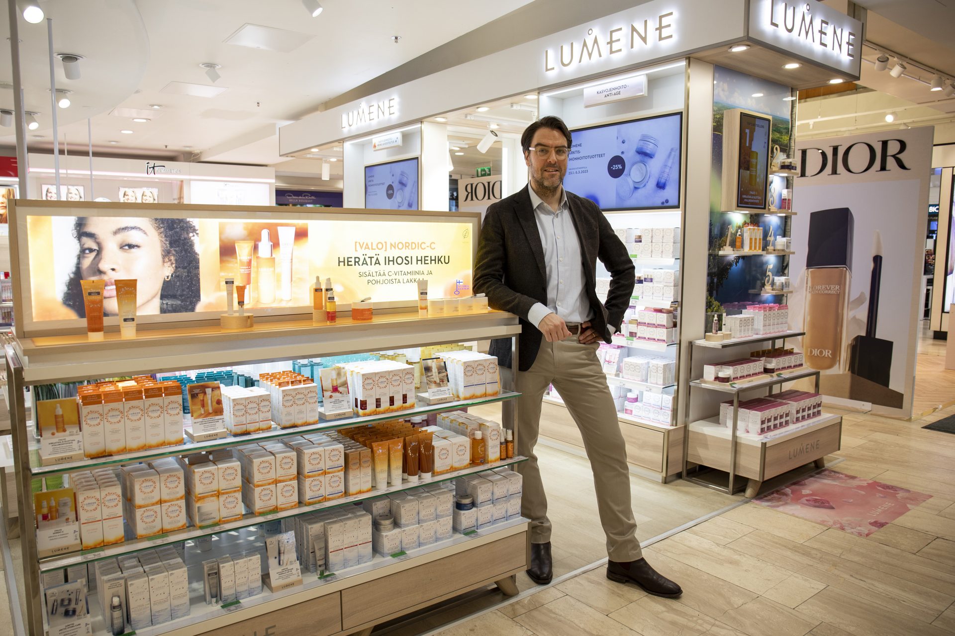 Martti at a Lumene department-store counter beside a lit NORDIC-C campaign panel