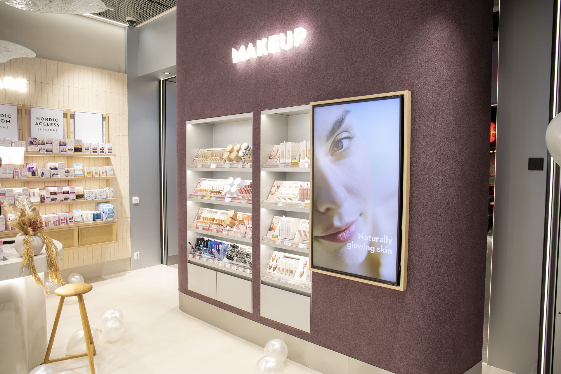 Lumene makeup wall with plum accent and lit shelving